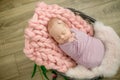 Perfect newborn baby girl in pink blanket in a wicker basket decorated with beautiful pink tulips