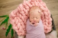 Perfect newborn baby girl in pink blanket in a wicker basket decorated with beautiful pink tulips