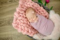 Perfect newborn baby girl in pink blanket in a wicker basket decorated with beautiful pink tulips