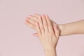 Perfect pink manicure on nails. Beautiful woman hand with clean skin over pink backdrop.