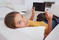 The perfect place for a bit of surfing. Portrait of a young woman using a digital tablet while lying on a sofa with her Royalty Free Stock Photo