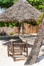 Perfect place for rest on a beach with thatched umbrella, wooden chair and hammock