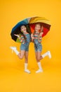 Perfect place to stay. small girl under colorful umbrella. two happy kids yellow background. children enjoy rainy autumn Royalty Free Stock Photo