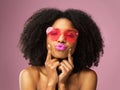 The perfect shade of pink for the perfect pout. Studio shot of an attractive young woman wearing heart shaped sunglasses