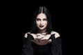 Perfect soothsayer woman with black hair, lips and nails looking at camera on black background Royalty Free Stock Photo