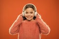 Perfect sound stereo headphones. Girl cute little child wear headphones listen music. Kid listen music orange background