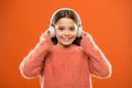 Perfect sound stereo headphones. Girl cute little child wear headphones listen music. Kid listen music orange background