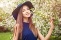 Perfect spring woman in blue hat outdoors. Smiling girl against flowers background