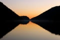 Perfect symmetrical reflection of mountain silhouette on a flat lake surface