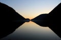 Perfect symmetrical reflection of mountain silhouette on a flat lake surface