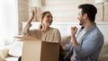 Overjoyed millennial married couple receiving big cardboard package by mail