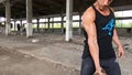 Strong guy workout his biceps with iron chain in old factory.