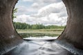 Perfect view from concrete drain pipe in the forest river. Beautiful water flow from the lake Royalty Free Stock Photo