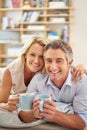 The perfect way to spend our day off. Portrait of a smiling mature couple lying on their living room floor drinking Royalty Free Stock Photo