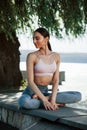 Perfect weather. Girl in sportive clothes sits outdoors near the tree