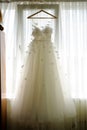 The perfect wedding dress with a full skirt on a hanger in the room of the bride with curtains Royalty Free Stock Photo