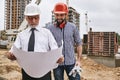 Perfect work. Main senior architect in formal wear and white helmet holding construction drawing and discussing it with Royalty Free Stock Photo