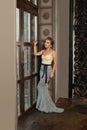 Perfect young adult model woman wearing fashionable evening gown in vintage palace room