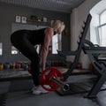 Perfect young woman with a sporty body is doing exercises with a barbell in the gym. Girl trains with a barbell indoors. Royalty Free Stock Photo