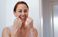 Perfect your smile by flossing regularly. Portrait of an attractive young woman flossing her teeth inside her bathroom Royalty Free Stock Photo