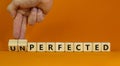 Perfected or unperfected symbol. Businessman turns wooden cubes and changes the word unperfected to perfected on a beautiful