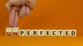 Perfected or unperfected symbol. Businessman turns wooden cubes and changes the word unperfected to perfected on a beautiful Royalty Free Stock Photo