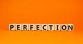 Perfection symbol. Wooden cubes with the word `perfection`. Beautiful orange table, orange background, copy space. Business and Royalty Free Stock Photo