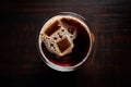 a perfectly chilled pint glass filled with dark beer, shot from above