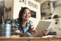 Perfectly content. Portrait of a young woman using a digital tablet at work.