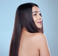 Perfectly content. Studio shot of a beautiful young woman showing off her long silky hair against a blue background.