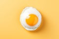 Perfectly cooked fried egg with golden yolk on vibrant yellow background, top view capture