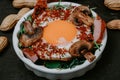 Perfectly cooked fried eggs with mushrooms, spices, pepper, meat and salt on arugula. Round breakfast plate on black plank with Royalty Free Stock Photo