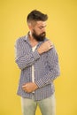 Perfectly imperfect. Fashion man dusting specks off his sleeve on yellow background. Bearded man in hipster fashion