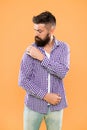 Perfectly imperfect. Fashion man dusting specks off his sleeve on yellow background. Bearded man in hipster fashion