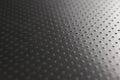 Perforated aluminum surface with many holes. Their ranks go into the distance and form a perspective. Industrial dark gray metal