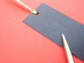 Perforated blue paper label, golden ribbon, and pen on red paper background.