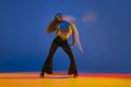 Performance. Portrait of young girl dancing heels dance in stylish clothes over blue background in neon with mixed Royalty Free Stock Photo