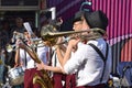 Performance of street musicians on a street in the city on the weekend. Small brass band: trumpeters, saxophonist, drummer