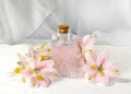 Perfume or aromatic oil glass with flowers over light background. Close up composition for spa, aromatherapy or massage. Royalty Free Stock Photo