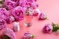 Perfume bottle around may roses against pink background. beauty concept