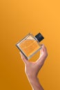 Perfume bottle in hands on an orange background. Royalty Free Stock Photo