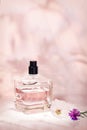 Perfume bottle with plants on a light pink floral background. Selective focus. Perfumery collection, cosmetics