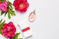 Perfume bottle and pink flowers peonies on light gray background top view Flat lay copy space. Perfumery, cosmetics, female Royalty Free Stock Photo