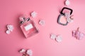 Perfume bottle with soft pink blush around flowers on pink background. flat lay