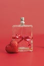 perfume bottle tied with a red festive ribbon among red heart on a red background,selective focus. Gift card for