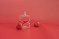 perfume bottle tied with a red festive ribbon among red hearts on a red background,selective focus. Gift card for