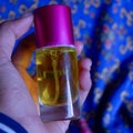 Perfume bottle with a yellow perfume color on a blue batik background Royalty Free Stock Photo