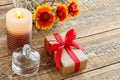 Perfume, gift box, candle and fresh flowers on wooden table