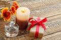 Perfume, gift box, candle and fresh flowers on wooden table