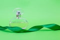 Perfume on a green background. Perfume with with a gift ribbon. Vintage perfume with a spray.